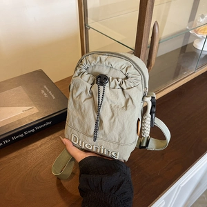 Green nylon crossbody bag with drawstring pocket and Duoning embroidery held by hand