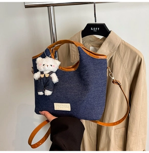 Detail of denim tote with brown leather trim, FFGDHM tag, and cute plush bear charm