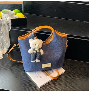 Detail of vintage denim underarm bag with leather handle and cute white bear charm