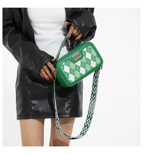 Detailed view of green argyle crossbody bag with adjustable geometric woven shoulder strap