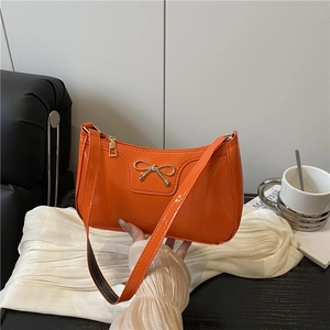 Bolso de hombro de charol naranja brillante con detalle de lazo metálico dorado