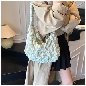 Close-up of mint green bubble textured fabric on a stylish crescent underarm bag