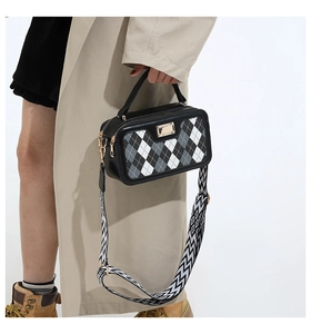 Detail of checkered box crossbody bag with wide shoulder strap and gold hardware