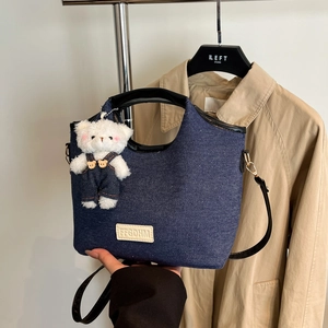 Deep blue denim underarm bag with plush bear charm and black leather shoulder strap