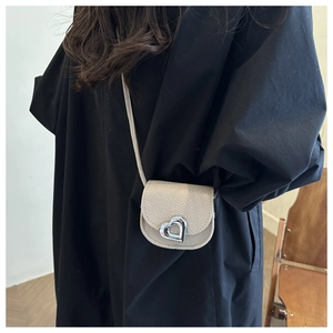 Détail du mini sac bandoulière en cuir gris avec fermoir métallique en forme de coeur