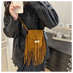 Dettaglio borsa a tracolla in camoscio marrone con frange e perline in legno per outfit