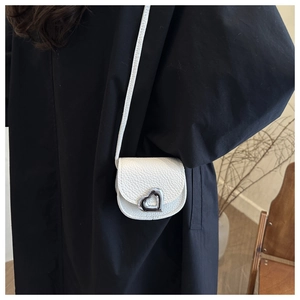 Detail of white lychee grain leather mini bag featuring a silver heart-shaped metal buckle