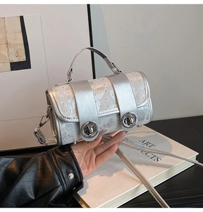 Detailaufnahme der silbernen Zylinderhandtasche mit zwei Metalldrehverschlüssen und Griff