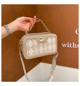 Detail of beige quilted handbag with metal clasp and patterned crossbody strap