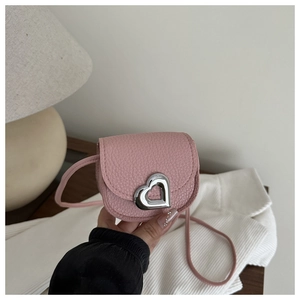 Detail of pink lychee leather handbag featuring a silver heart-shaped metal buckle