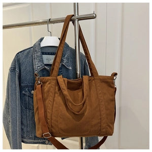 Detail of brown corduroy tote bag showing vertical striped texture and metal side buckles