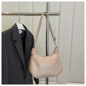 Detail view of beige crescent bag featuring smooth PU leather and adjustable metal buckle strap