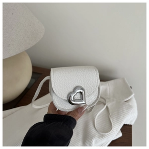 Detail of mini white pebbled leather crossbody bag with silver heart buckle accent