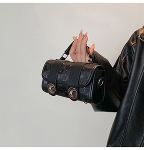 Detail of black cylindrical handbag featuring star-texture faux leather and metal buckles