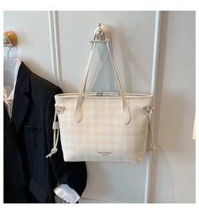 Detail of checkered tote bag with drawstring sides and polished metal hardware accents