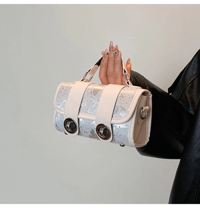 Detail of silver sequin handbag featuring white leather trim and dual metal twist locks