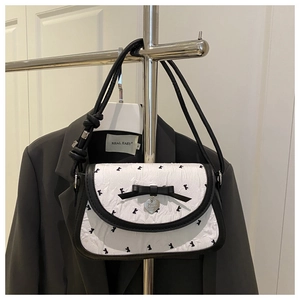 Detail of the bow decoration and silver heart pendant on the pleated handbag
