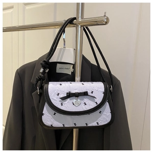 Detail of light blue pleated handbag with black bow and silver heart pendant charm