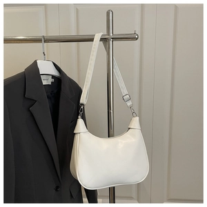 Detail of white leather crescent bag hanging on a hanger with silver buckle accents