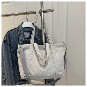 Light grey corduroy tote bag with adjustable strap displayed on a minimalist hanger