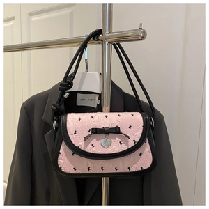 Detail of pink bow handbag with black leather accents and silver heart pendant charm