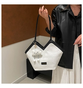 Detail of white corduroy tote bag with black leather straps and cloud plush charm