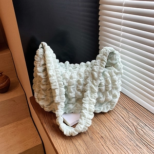 Pleated bubble fabric shoulder bag in mint green on a wooden bench with lifestyle aesthetic