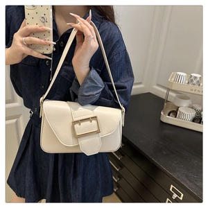 Detail of a creamy white PU leather baguette bag with a large golden metal buckle