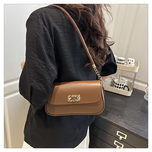 Détail d'un sac à bandoulière en cuir marron avec fermoir doré et bandoulière en chaîne