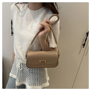 Gros plan sur la texture du cuir marron et le fermoir en métal doré du petit sac carré