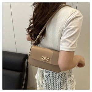 Détail du sac sous l'aisselle beige minimaliste avec boucle en métal doré tissé