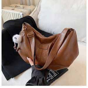 Brown faux leather tote bag with unique texture, adjustable strap and plush charm detail