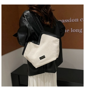 Detail of white corduroy tote bag with black leather straps and fashion label