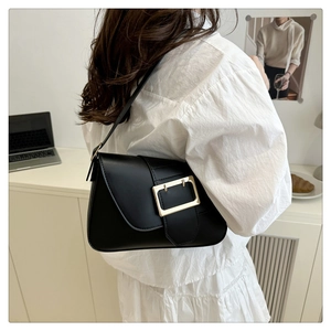 Minimalist black leather underarm bag with gold buckle shown on a model's shoulder