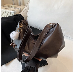 Detail of vintage brown PU leather tote bag with grainy texture and plush charm