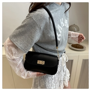 Détail du sac bandoulière en cuir noir avec boucle dorée tressée et fine bandoulière