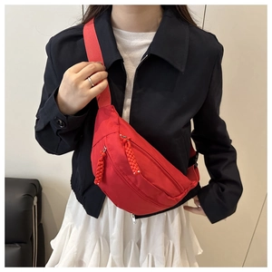Detail of red crossbody chest bag with adjustable strap and woven zipper pulls
