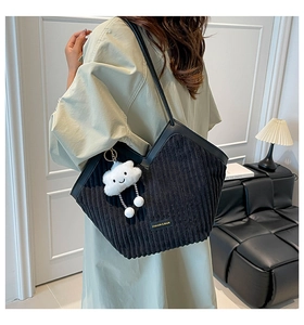 Detail of black corduroy tote bag featuring a leather strap and cute cloud charm accessory