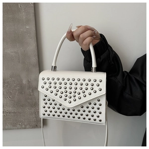 Detail of white square handbag with silver studs, round top handle, and leather texture