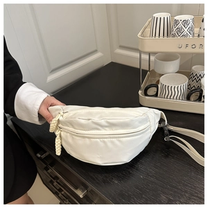 Detailed macro view of white nylon waist bag texture and cream braided zipper pull detail