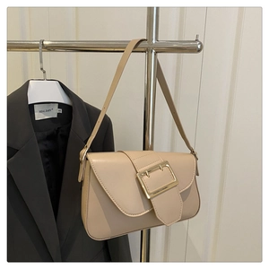 Detailed view of the beige underarm bag featuring a large decorative gold square buckle