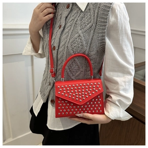 Detailed view of red leather crossbody bag with silver studs and envelope flap design