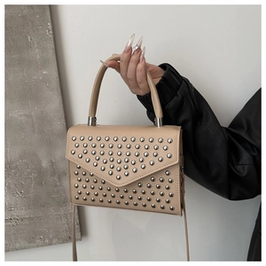 Close-up of beige square handbag with silver metal studs and leather texture detail