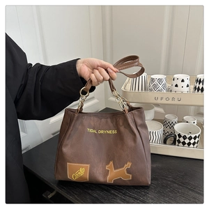 Detail of brown PU tote bag with metal chain handle and TIDAL DRYNESS slogan