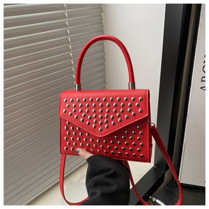 Detail of red faux leather handbag featuring silver studs and top handle for women