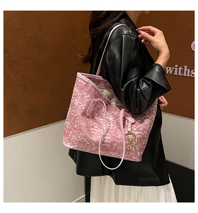 Dettaglio della borsa tote a scacchi rosa e bianca con ciondolo a M dorato e manici sottili