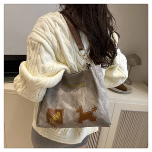 Detail of grey canvas tote bag featuring brown leather straps and embroidered dog patch