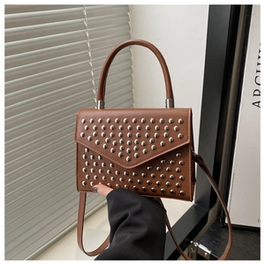 Detail of brown leather handbag with silver studs and a classic curved top handle