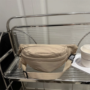 Minimalist beige crossbody dumpling bag on glass shelf with modern urban lifestyle decor
