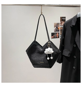 Detail of black corduroy tote bag with V-shaped opening and cloud charm accessory